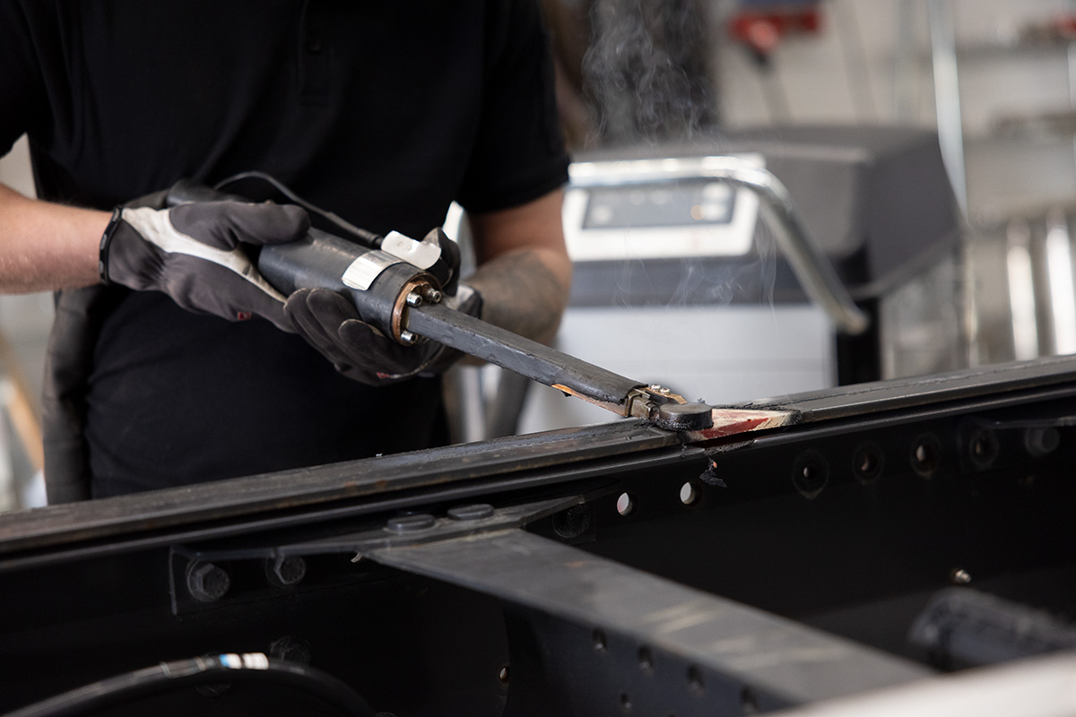 Close up of a technician using JOSAM JH1500 induction heater to heat part of a truck frame