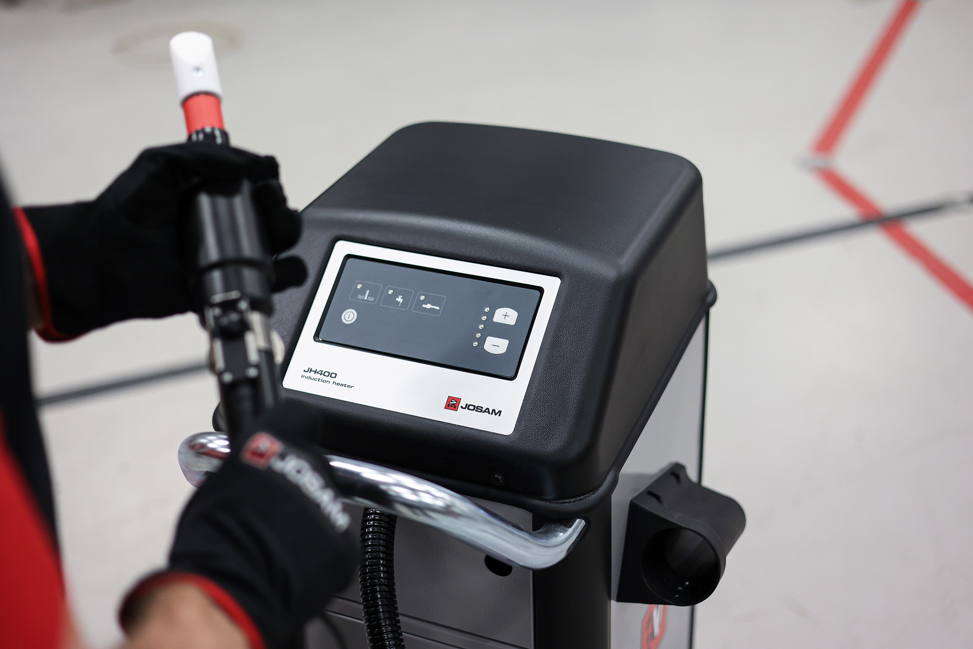 A technician holding JOSAM JH400 inductor with machine in the mid-ground 