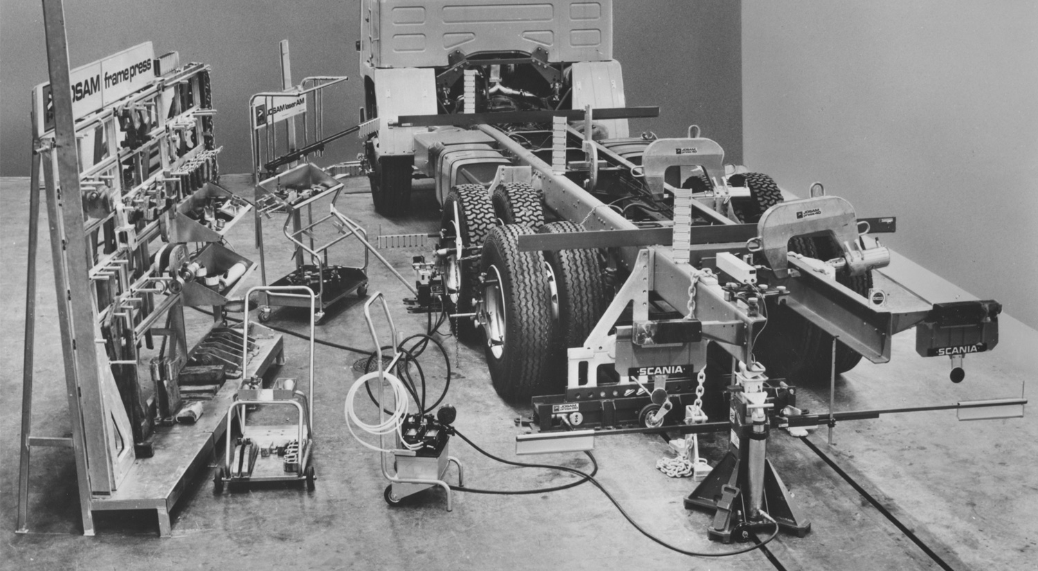 A black and white photo of a truck being repaired using JOSAM equipment
