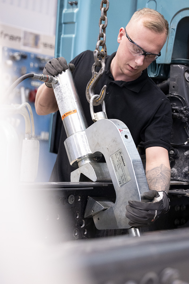 Technician using hydraulic clamp on a truck frame